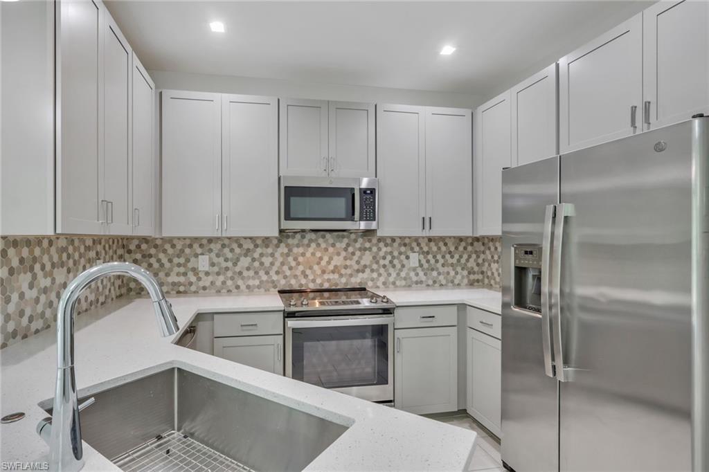 7501 Carnegie Way Naples, FL 34119 - Photo 5 of 37 Kitchen featuring stainless steel appliances, tasteful backsplash, and light stone countertops