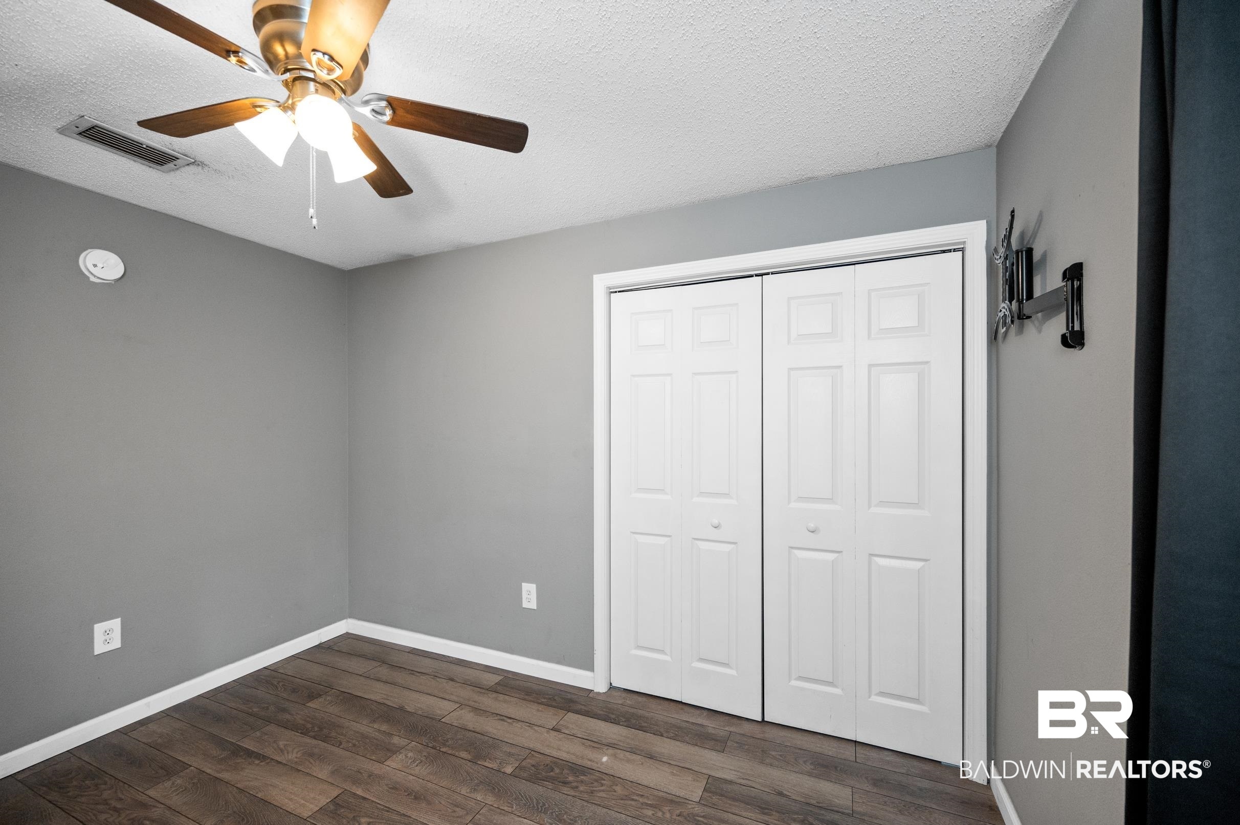 906 North Cedar Street Foley, AL 36535 - Photo 17 of 24 Unfurnished bedroom with ceiling fan, a textured ceiling, a closet, and dark hardwood / wood-style flooring