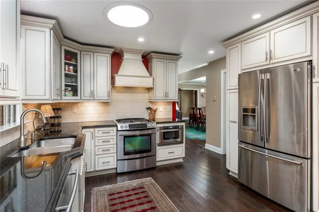 a kitchen with stainless steel appliances granite countertop a stove a sink dishwasher a refrigerator and a stove with wooden floor