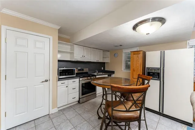 a kitchen with stainless steel appliances granite countertop a white table and chairs