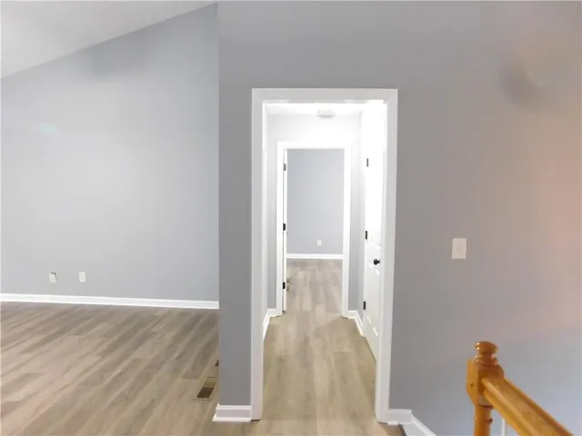 a view of a hallway with wooden floor and a livingroom