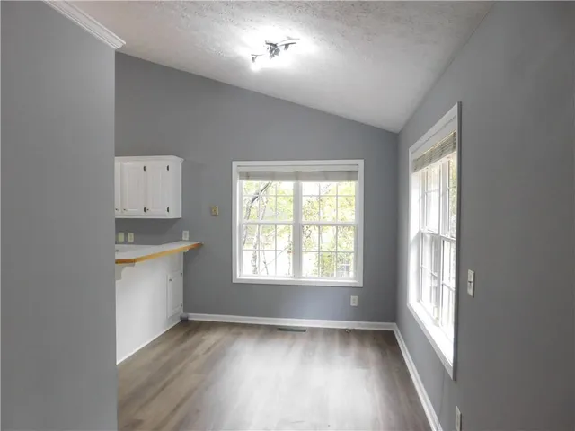 a view of an empty room with a window and wooden floor