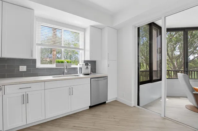 a kitchen with white cabinets and a large window