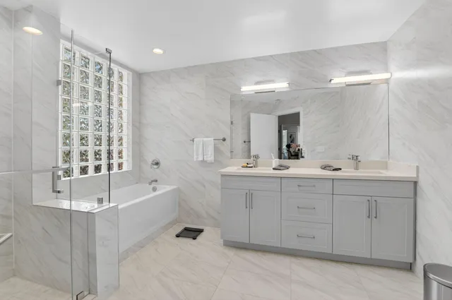 a spacious bathroom with a double vanity sink a mirror and a bathtub