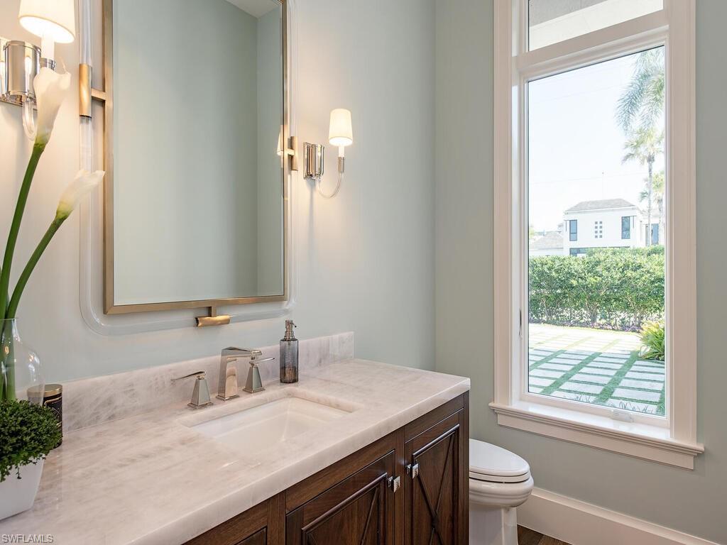 3320 Rum Row Naples, FL 34102 - Photo 26 of 39 a bathroom with a granite countertop sink a toilet a mirror and a window