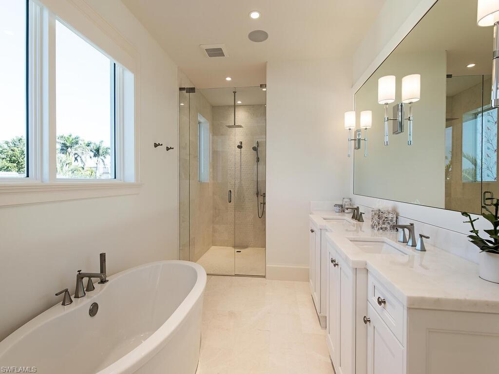 3320 Rum Row Naples, FL 34102 - Photo 30 of 39 a bathroom with a tub sink double vanity and a mirror