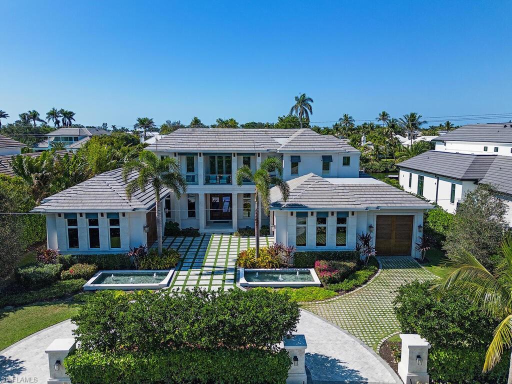 3320 Rum Row Naples, FL 34102 - Photo 6 of 39 a view of a white house with a big yard and potted plants