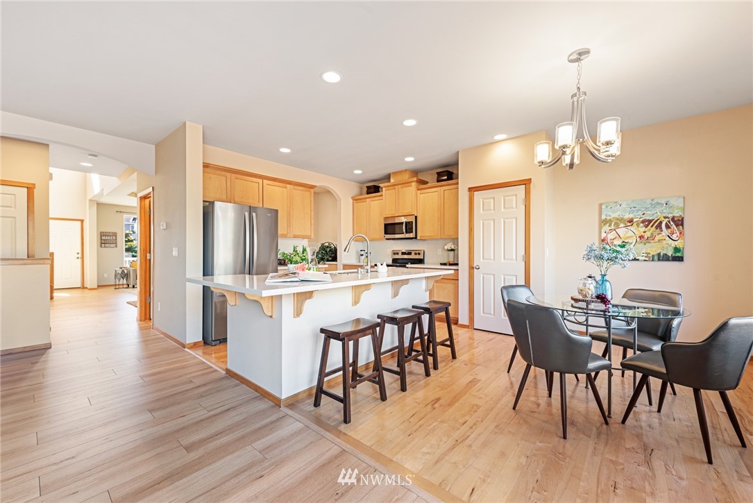 21215 40th Drive Southeast Bothell, WA 98021 - Photo 8 of 25 a kitchen with stainless steel appliances kitchen island granite countertop a dining table chairs and white cabinets