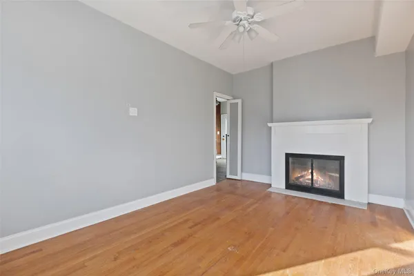 a view of an empty room with chandelier fan and fire place