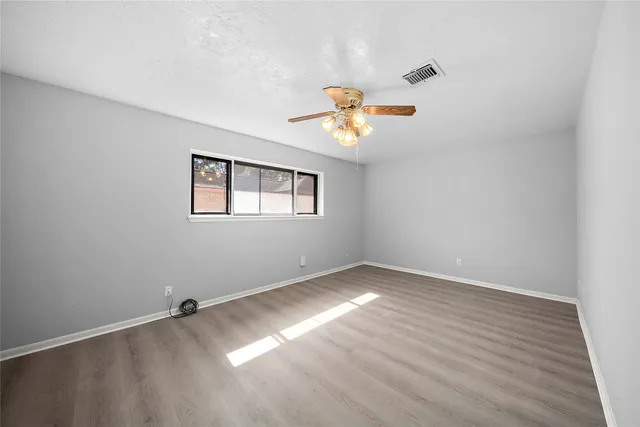 an empty room with a window and a ceiling fan