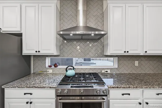 a kitchen with granite countertop white cabinets and stainless steel appliances