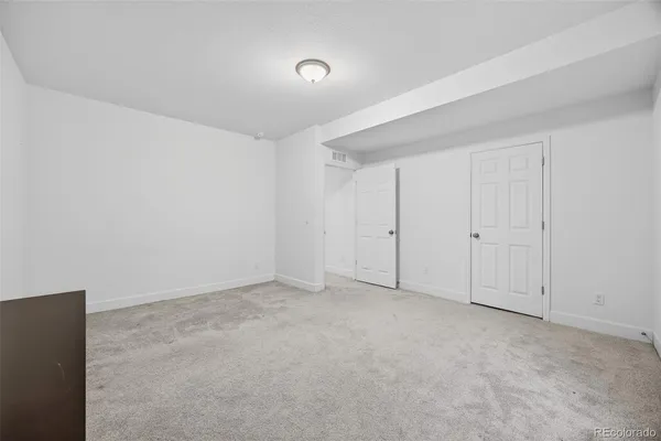 a bedroom with a bed a couch and a flat tv screen on the dresser