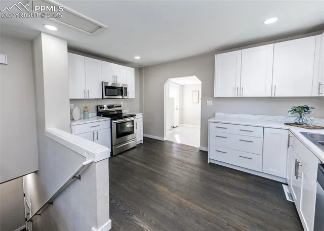 a kitchen with granite countertop a refrigerator and a stove top oven