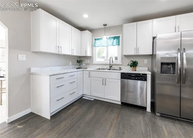 a kitchen with white cabinets stainless steel appliances and a window