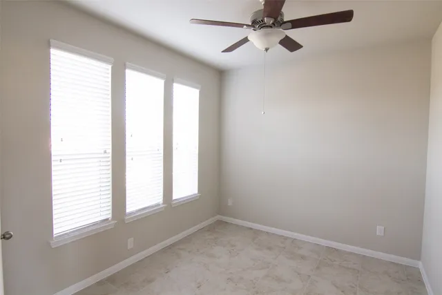 an empty room with a window and a fan