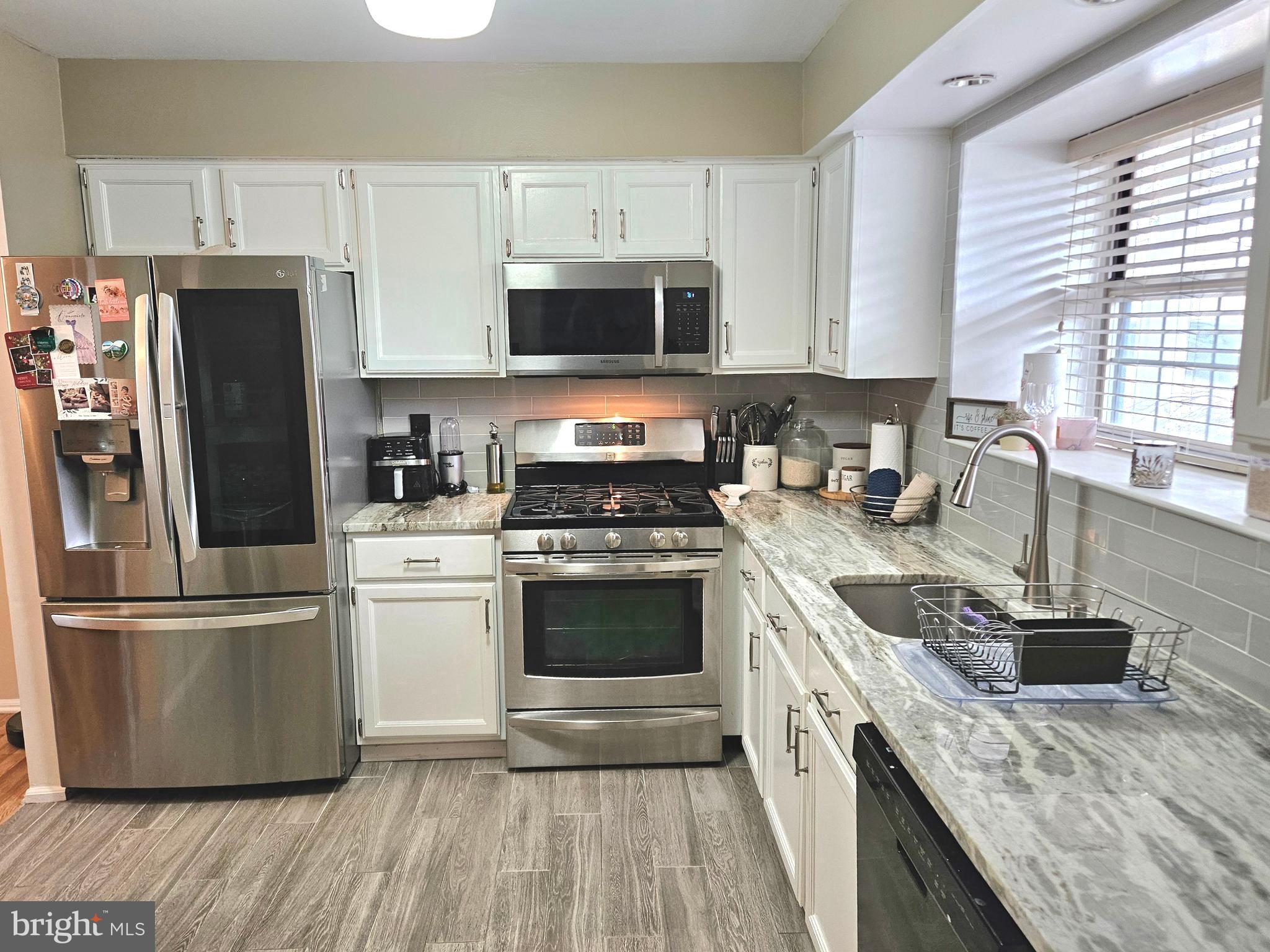 17 Exeter Court Bordentown, NJ 08505 - Photo 3 of 19 a kitchen with stainless steel appliances granite countertop a stove a refrigerator and a sink with wooden floors