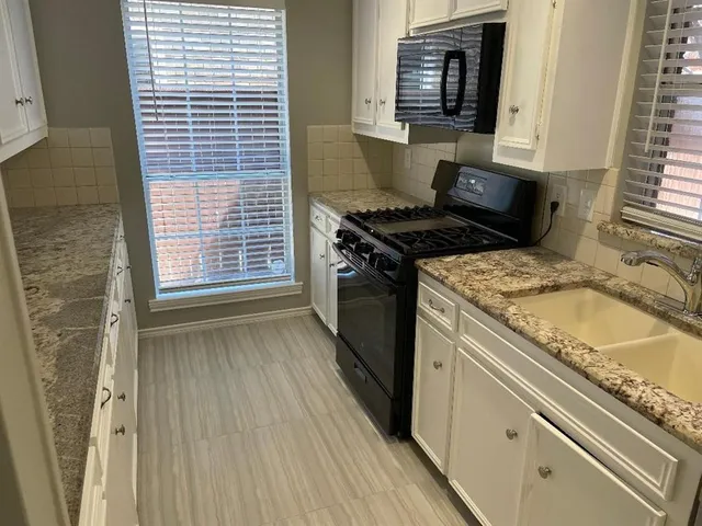 a kitchen with granite countertop a sink stove and cabinets