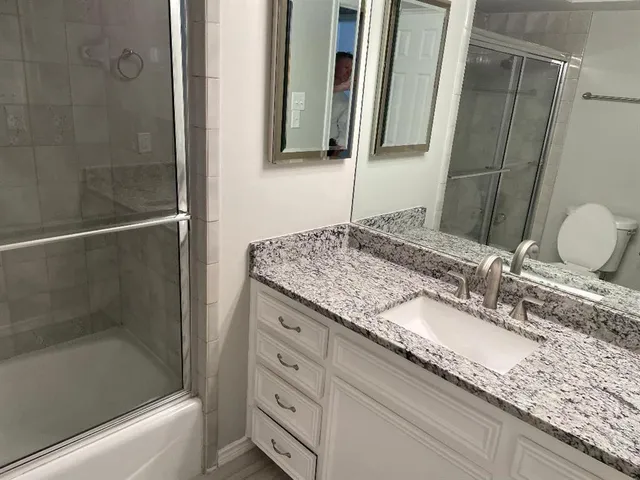 a bathroom with a granite countertop sink and a mirror