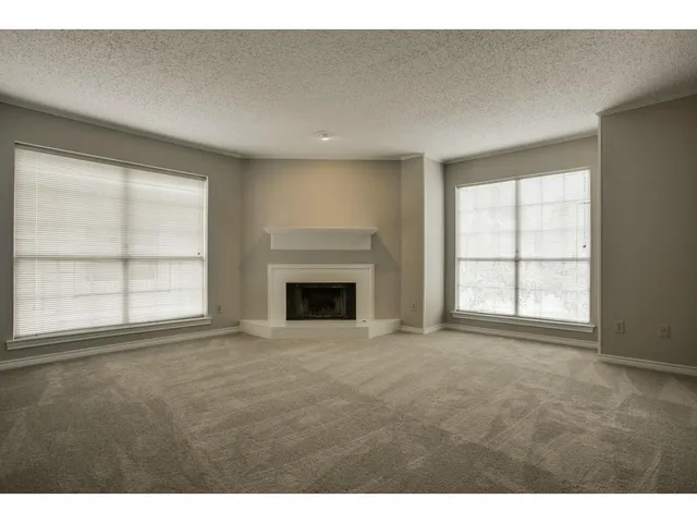 an empty room with windows and fireplace