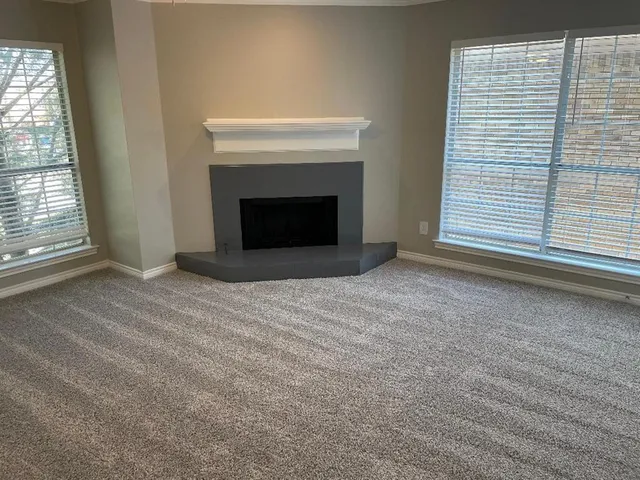 a view of an empty room with a fireplace and a window