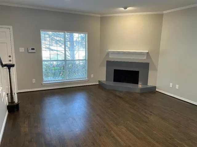 an empty room with wooden floor fireplace and windows