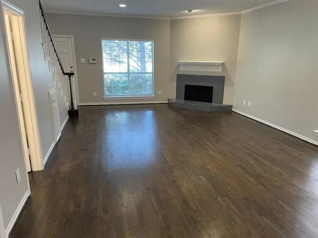 an empty room with wooden floor fireplace and windows