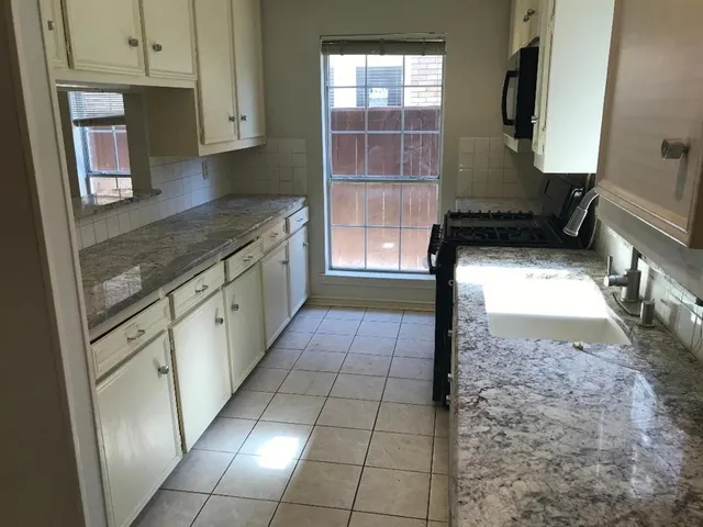 a kitchen with granite countertop a rug a stove a microwave and a counter top space