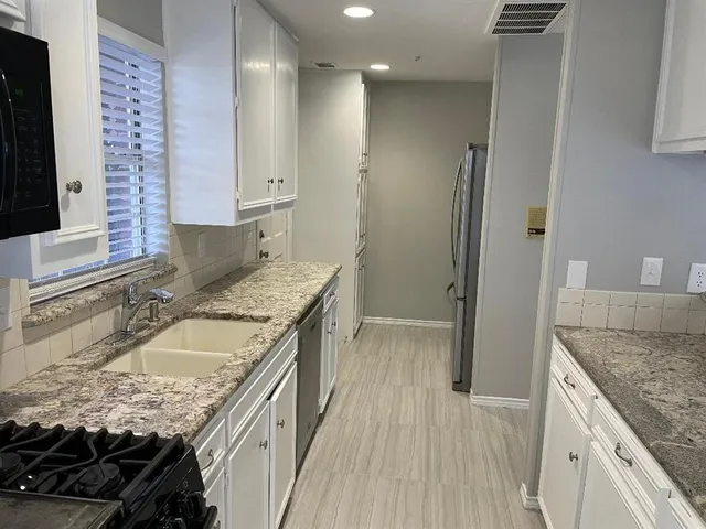 a kitchen with granite countertop kitchen island stainless steel appliances a sink stove and refrigerator