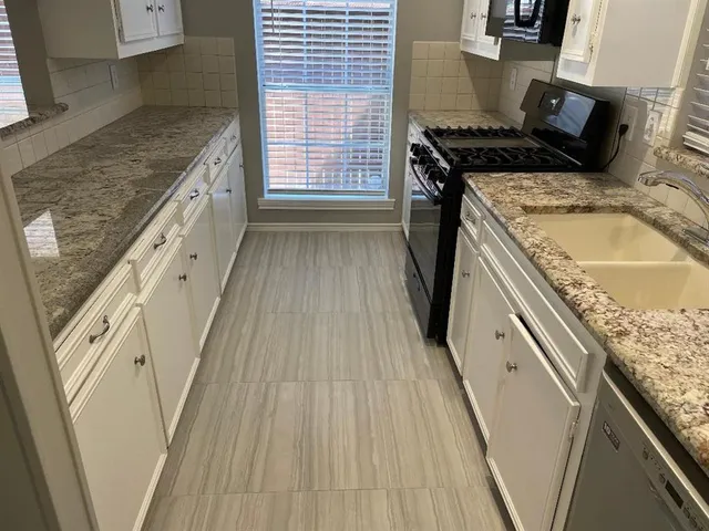 a kitchen with granite countertop a sink stove and refrigerator