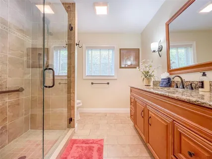 a bathroom with a granite countertop sink a mirror and shower