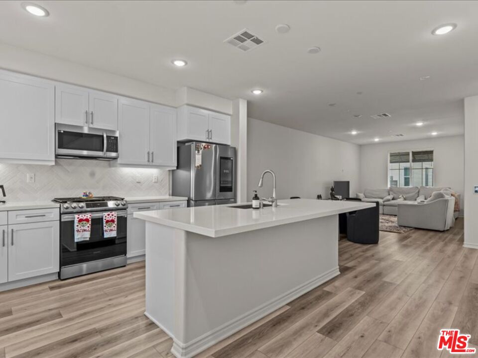 a large kitchen with kitchen island a sink a counter top space stainless steel appliances and cabinets
