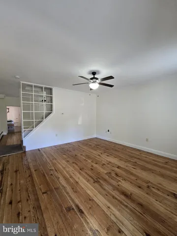 a view of a livingroom with wooden floor and ceiling fan