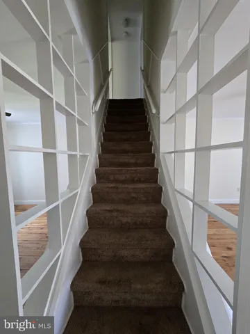 a view of staircase with wooden floor and white walls