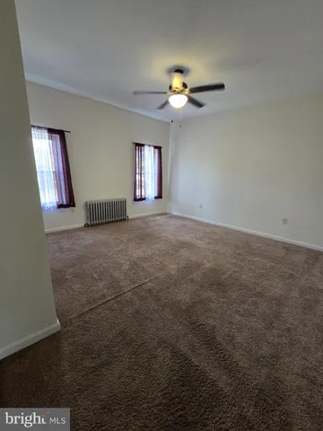 an empty room with windows and chandelier fan