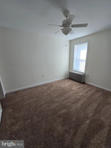 an empty room with a ceiling fan and window