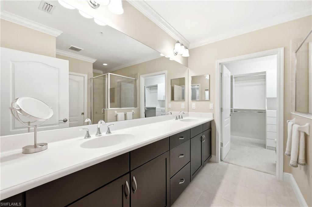 6980 Avalon Circle, Unit 1102 Naples, FL 34112 - Photo 11 of 24 Bathroom with a shower stall, ornamental molding, a spacious closet, double vanity, and light tile patterned flooring