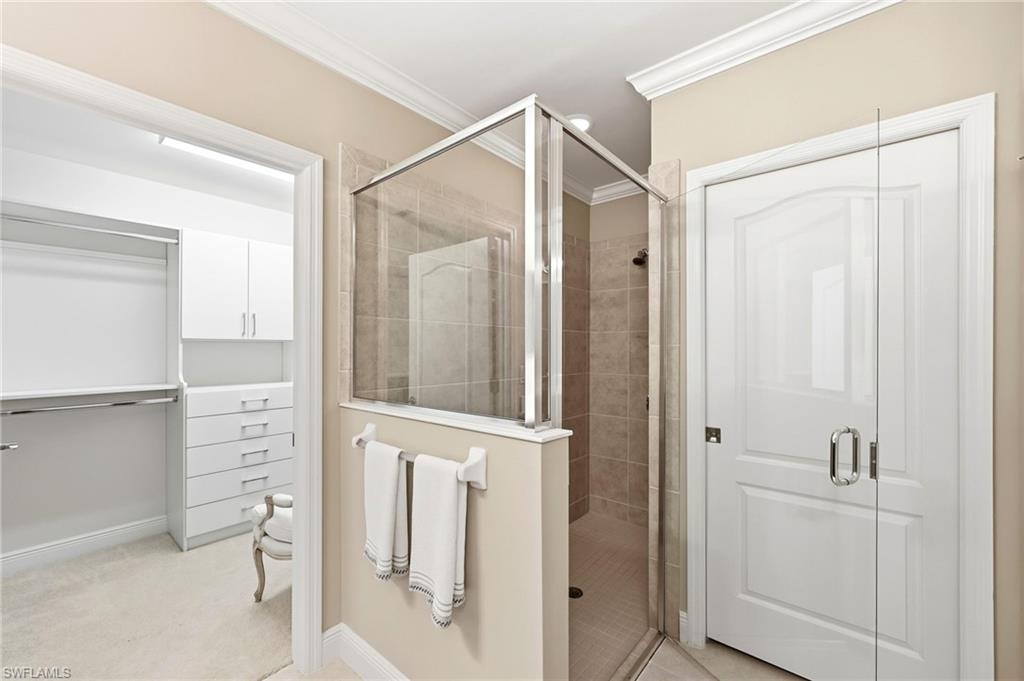 6980 Avalon Circle, Unit 1102 Naples, FL 34112 - Photo 12 of 24 Full bathroom featuring a stall shower, a spacious closet, ornamental molding, and light carpet