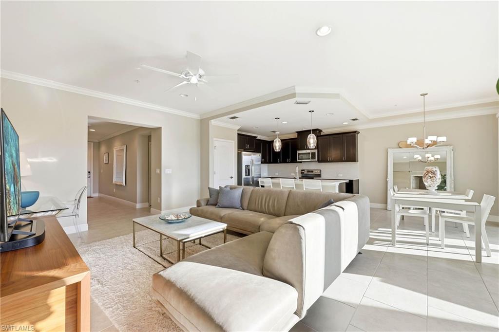 6980 Avalon Circle, Unit 1102 Naples, FL 34112 - Photo 3 of 24 Living area with ornamental molding, light tile patterned floors, suspended lighting, and ceiling fan