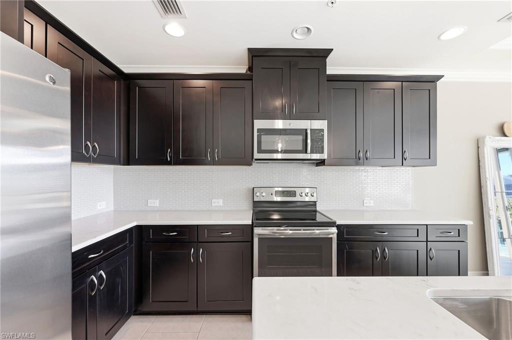 6980 Avalon Circle, Unit 1102 Naples, FL 34112 - Photo 6 of 24 Kitchen with stainless steel appliances, light stone counters, decorative backsplash, and recessed lighting