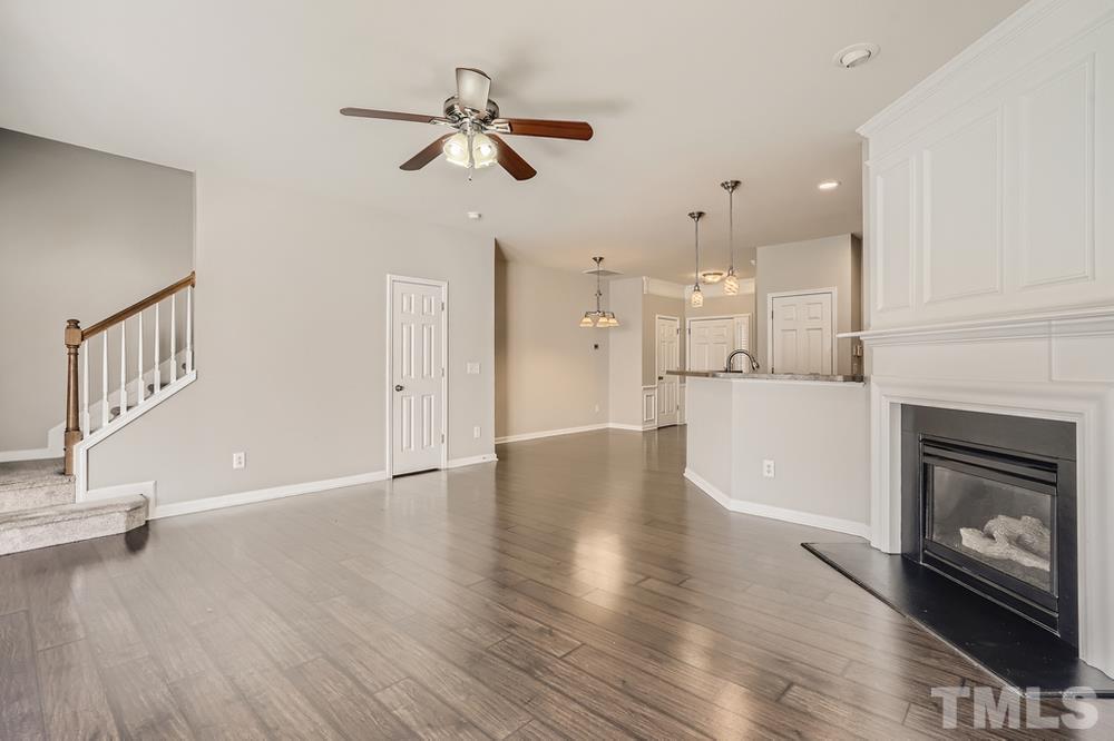 7222 Racine Way Raleigh, NC 27615 - Photo 8 of 27 a view of a kitchen and an empty room with wooden floor and a fireplace