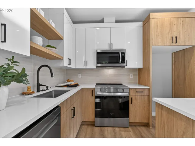 a kitchen with stainless steel appliances a stove a sink a microwave and cabinets