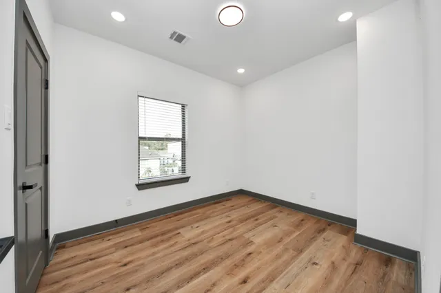 an empty room with wooden floor and windows