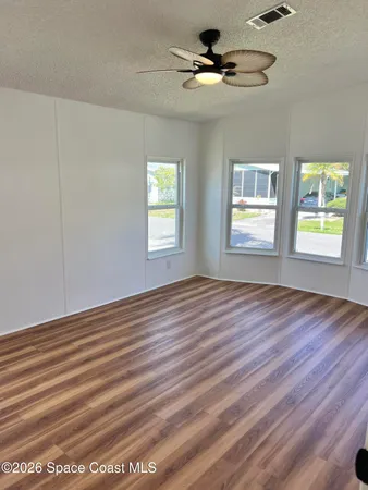 a view of an empty room with a window and wooden floor