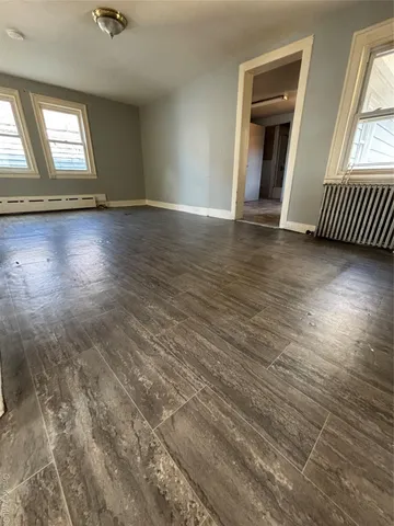 a view of an empty room with window and wooden floor