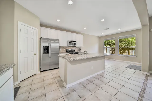 a kitchen with white cabinets a counter top space and stainless steel appliances