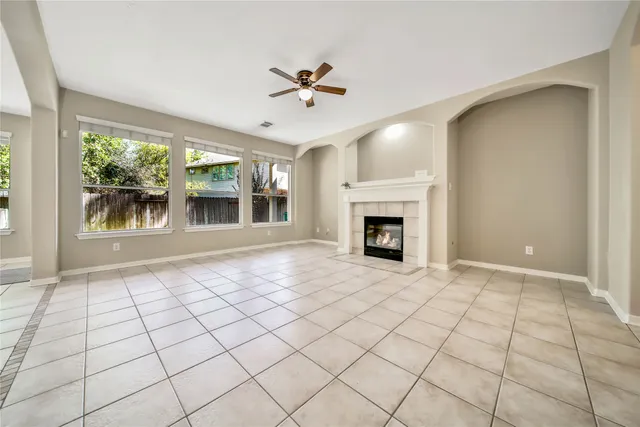 a view of an empty room with window and chandelier fan