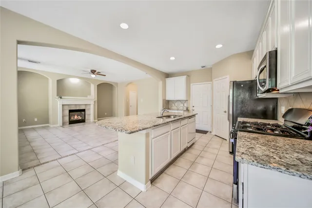 a kitchen with stainless steel appliances granite countertop a stove top oven a sink and a refrigerator