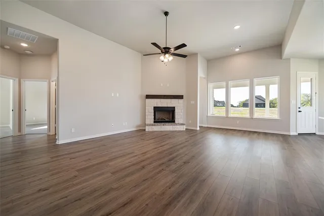 a view of an empty room with wooden floor and a fireplace