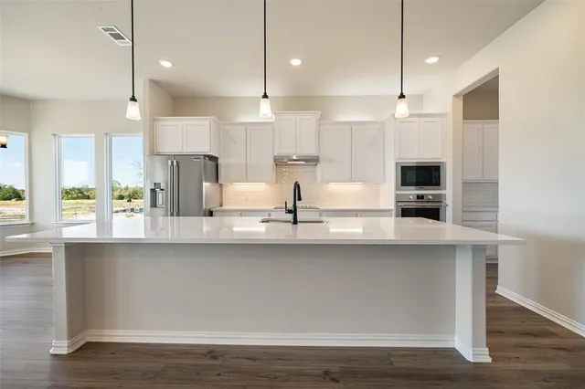 a kitchen with kitchen island a sink stainless steel appliances and wooden floor