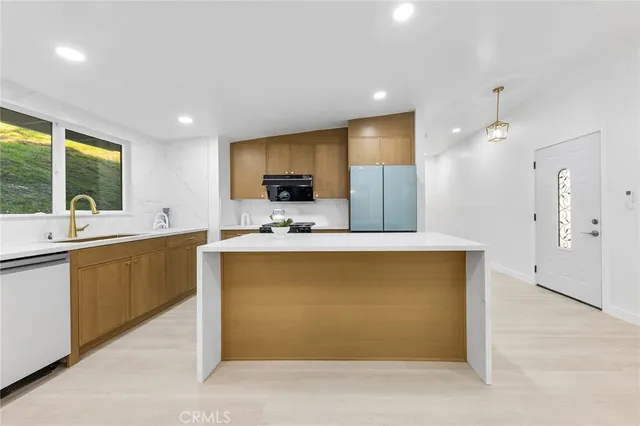 a view of kitchen with stainless steel appliances kitchen island sink refrigerator and window